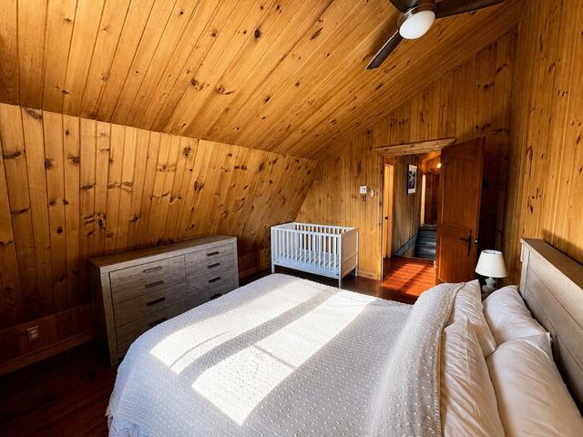 The king bedroom with pine walls and a dark wood bed