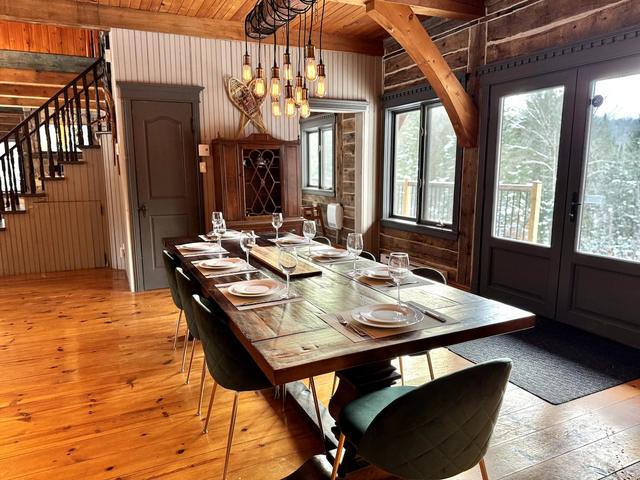 The long dining table set for dinner beside the staircase