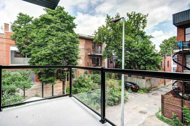 The rear balcony with glass railing over trees and neighbouring rooftops