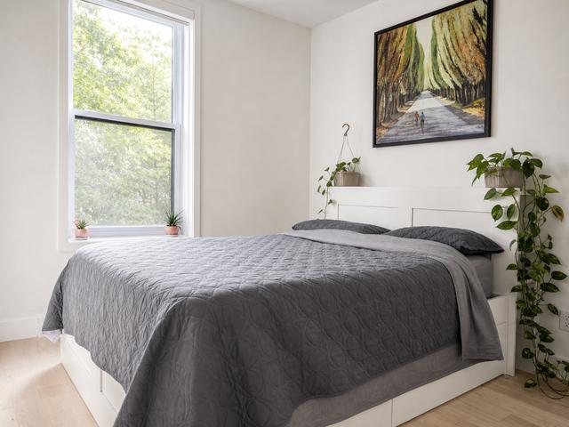 A queen bedroom with a window onto the trees and a landscape painting
