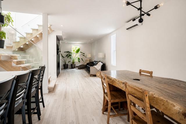 The live-edge wood dining table under a branching pendant, staircase beyond