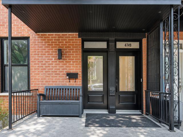 The red-brick front entry with black door and wrought-iron railing