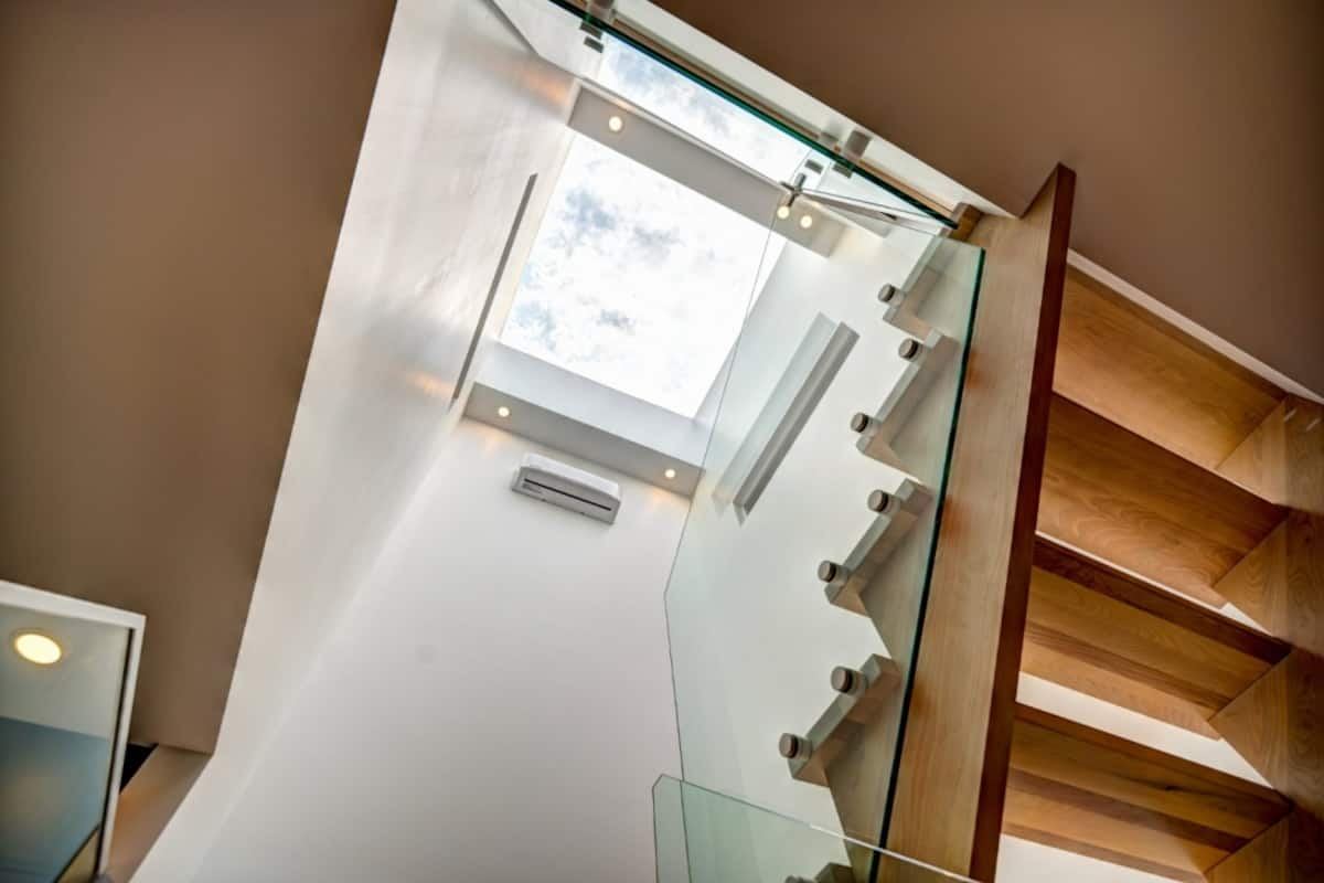 Looking up the floating maple staircase with glass rail to the oversized skylight