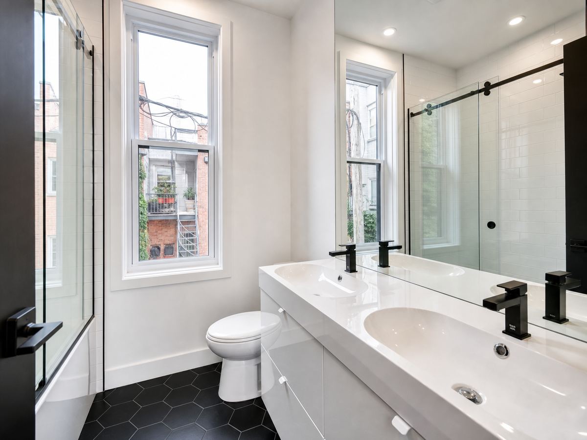 The double vanity with two black faucets and a window