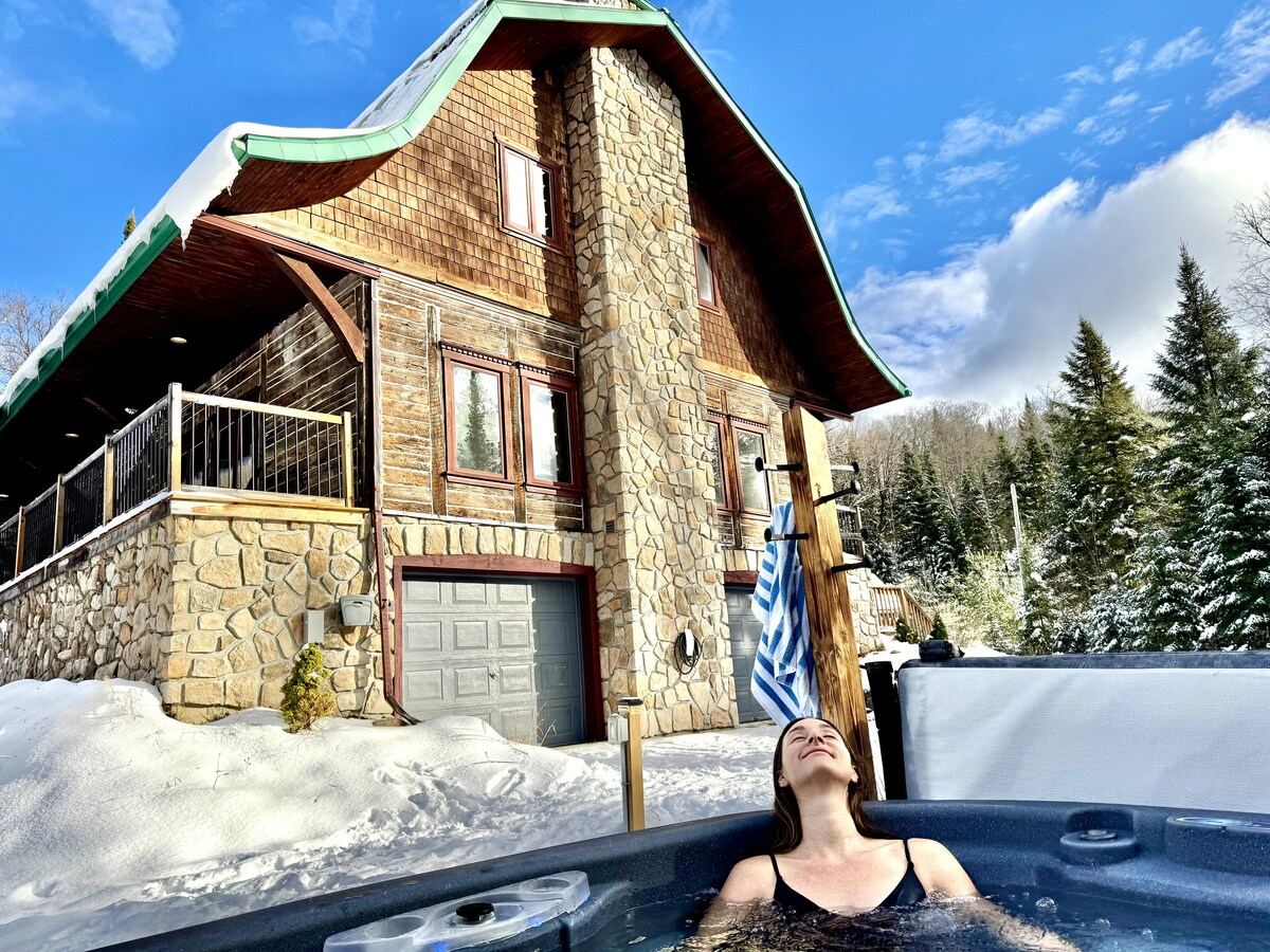 A guest in the hot tub in winter with the log gable of the house above